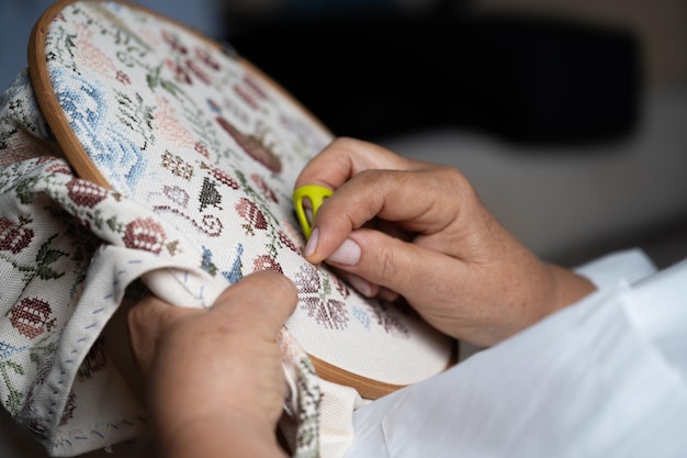 Mâini care brodează un model floral